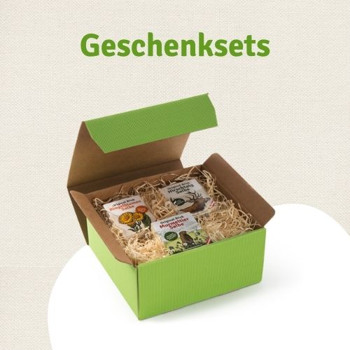 Foto auf der Seite Murmeltier Salbe kaufen - Text Geschenksets und zu sehen ist eine grüne Geschenksbox mit Holzwolle und drei Cremen. Es bfinden sich Ringelblumen Salbe, Hirschtalg und Murmeltiersalbe in der Box.